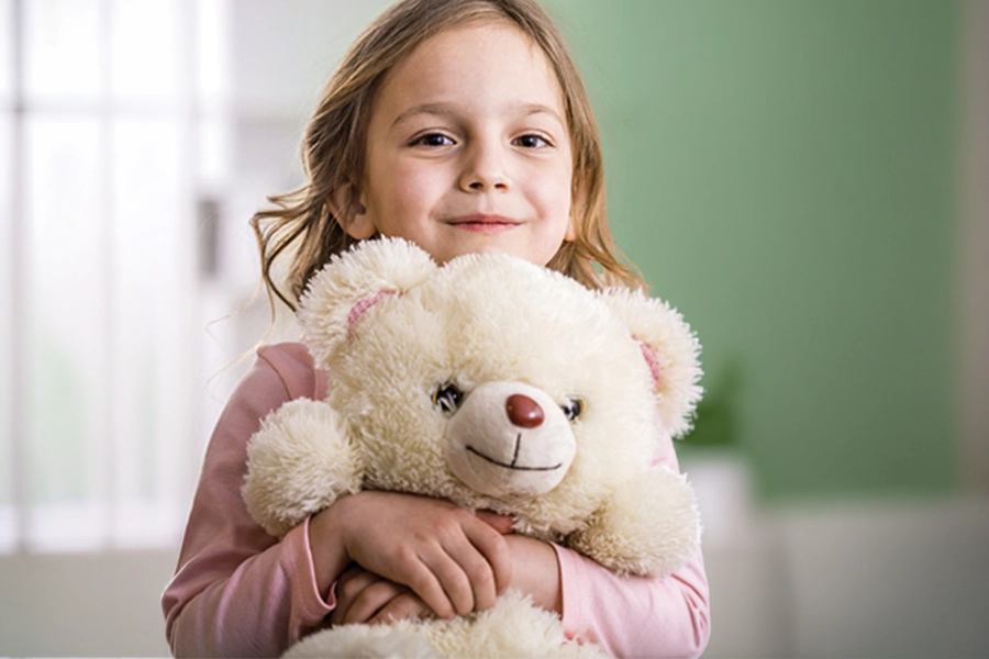 Young girl holding white teddy bear